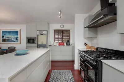 a kitchen with white counters and a stove top oven at Die Rietdak - Reetdachhaus mit vier Schlafzimmern in Cape Town