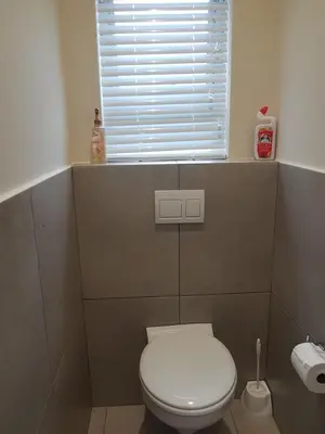 a bathroom with a white toilet and a window at Sharon's House: Modern Self-Catering rooms in Cape Town