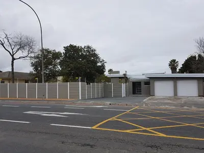 a parking lot with a white fence and a building at Sharon's House: Modern Self-Catering rooms in Cape Town