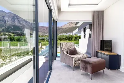 a living room with a chair and a television at Villa de luxe in Franschhoek
