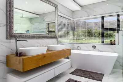 a bathroom with two sinks and a tub and a mirror at Villa de luxe in Franschhoek