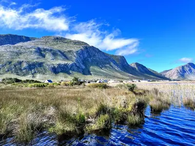 a mountain in the middle of a field with water at Silverdunes - GardenView in Bettyʼs Bay