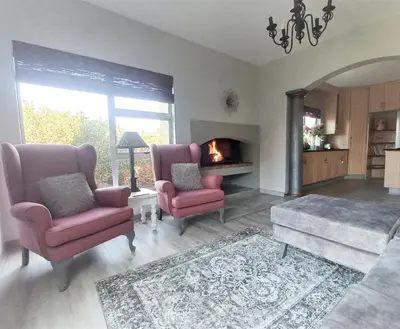 a living room with two chairs and a fireplace at Silverdunes - GardenView in Bettyʼs Bay