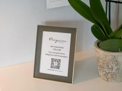 a sign on a table next to a plant at Penguino Guesthouse in Hermanus
