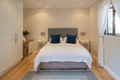 a bedroom with a large bed with blue pillows at Penguino Guesthouse in Hermanus