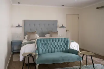 a bedroom with a bed and a blue chair at Penguino Guesthouse in Hermanus