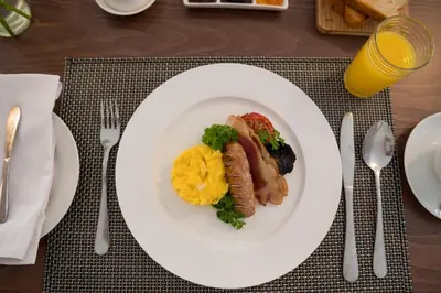 a plate of food with sausage and broccoli on a table at Penguino Guesthouse in Hermanus