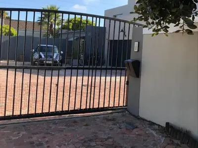 a black fence with a car parked in a parking lot at Blouberg Studio Apartment in Bloubergstrand