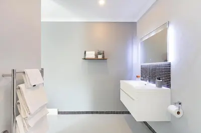 a white bathroom with a sink and a mirror at Blouberg Studio Apartment in Bloubergstrand