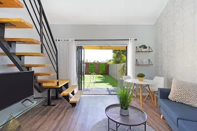 a living room with a blue couch and a staircase at Blouberg Studio Apartment in Bloubergstrand