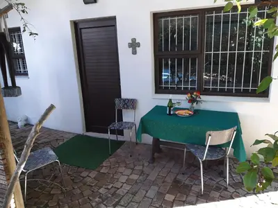 a green table and chairs in a room with a window at 16 Rhodes-North Self Catering Apartment & Studio in Stellenbosch