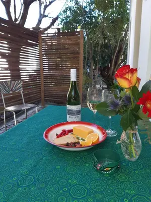 a table with a plate of cheese and a bottle of wine at 16 Rhodes-North Self Catering Apartment & Studio in Stellenbosch