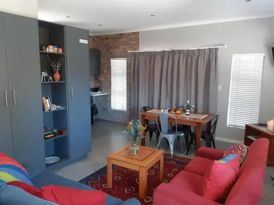 a living room with a table and red chairs at 16 Rhodes-North Self Catering Apartment & Studio in Stellenbosch