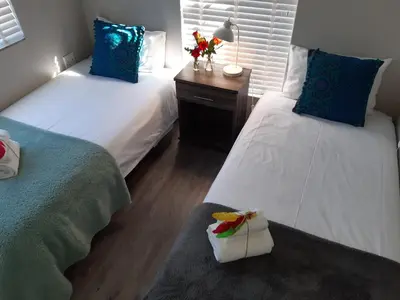 a bedroom with two beds and a table with flowers on it at 16 Rhodes-North Self Catering Apartment & Studio in Stellenbosch