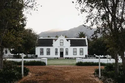 a white house with mountains in the background at Weltevreden Estate in Stellenbosch