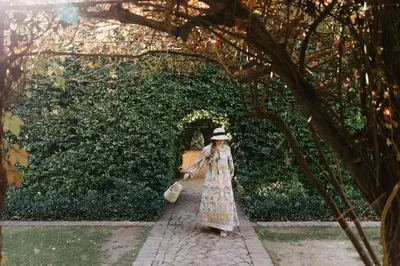 a woman in a dress and hat walking down a sidewalk at Weltevreden Estate in Stellenbosch