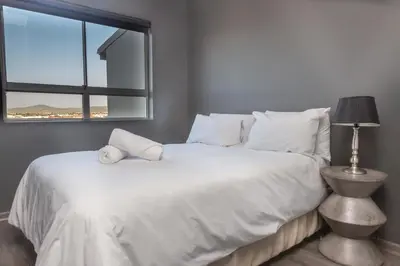 a bedroom with a large white bed with a window at Spacious Luxury 3 Bedroom Apartment B401 Sea Spray in Bloubergstrand