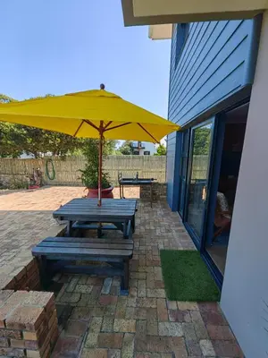a picnic table with an umbrella on a brick patio at Karibu Self-catering Accommodation in Hermanus
