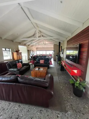 a living room with leather furniture and a flat screen tv at Karibu Self-catering Accommodation in Hermanus