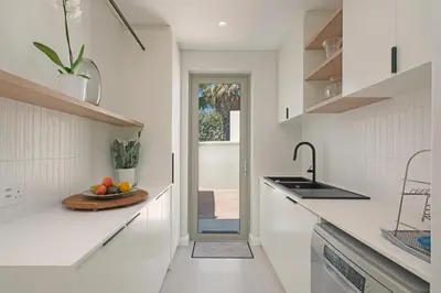 a white kitchen with a bowl of fruit on the counter at Kite View Villa @2 in Cape Town