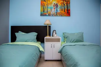 a bedroom with two beds and a painting on the wall at Relaxing Guest House in th Heart of Ndabeni in Cape Town