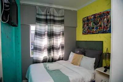 a bedroom with a bed and a painting on the wall at Relaxing Guest House in th Heart of Ndabeni in Cape Town