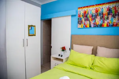a bedroom with a green bed and a painting on the wall at Relaxing Guest House in th Heart of Ndabeni in Cape Town