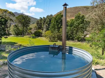 a large tank of water with a bird perched on top at La Ferme Guest Farm - Hot Tubs in Franschhoek