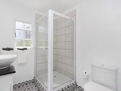 a white bathroom with a shower and a sink at La Ferme Guest Farm - Hot Tubs in Franschhoek