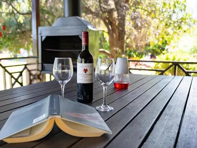 a bottle of wine and two glasses on a wooden table at La Ferme Guest Farm - Hot Tubs in Franschhoek