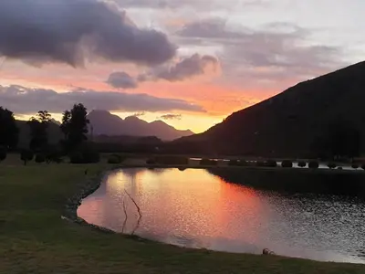 a body of water with a sunset in the background at La Ferme Guest Farm - Hot Tubs in Franschhoek