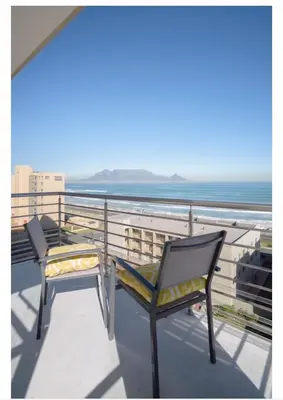two chairs sitting on a balcony overlooking the ocean at Designer Flat with scenic views in Cape Town