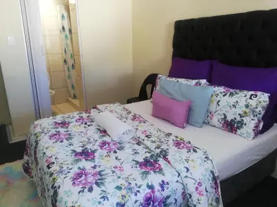 a bedroom with a bed with purple and pink pillows at MJ ACCOMODATION in Cape Town