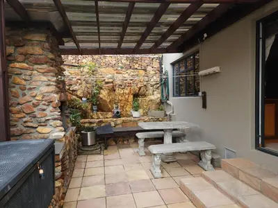 a patio with a bench and a stone wall at Perhethian in Cape Town