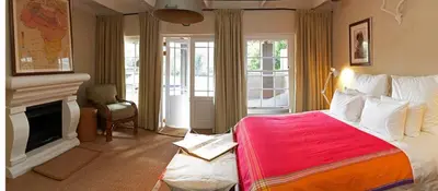 a bedroom with a large bed and a fireplace at Explorers Club in Franschhoek