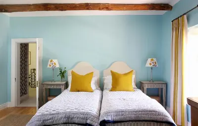 two beds in a bedroom with blue walls and yellow pillows at Tugela in Franschhoek