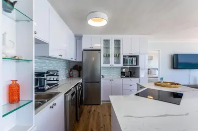 a kitchen with white cabinets and a stainless steel refrigerator at Ocean View A1101 by CTHA in Bloubergstrand