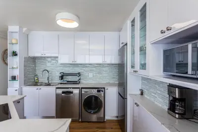 a kitchen with white cabinets and a washer and dryer at Ocean View A1101 by CTHA in Bloubergstrand