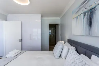 a bedroom with a large bed with white sheets and pillows at Ocean View A1101 by CTHA in Bloubergstrand