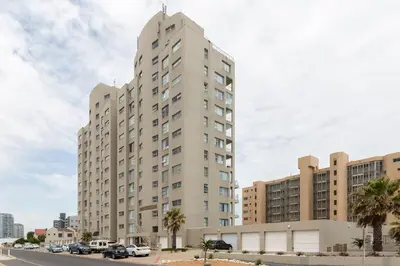 a tall building with cars parked in front of it at Ocean View A1101 by CTHA in Bloubergstrand