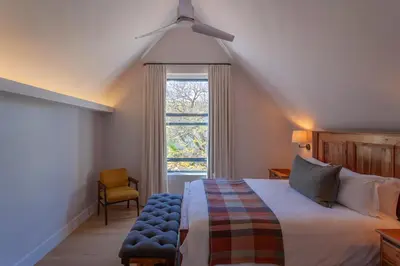 a bedroom with a bed and a window and a chair at Minserie Collection in Stellenbosch