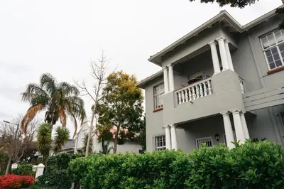 a white house with a balcony and palm trees at Minserie Collection in Stellenbosch
