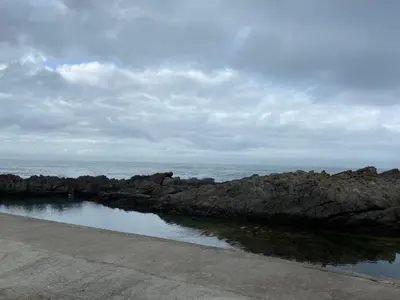 a group of rocks and the ocean on a cloudy day at Hemel in Hermanus Three bedroom Home in Hermanus