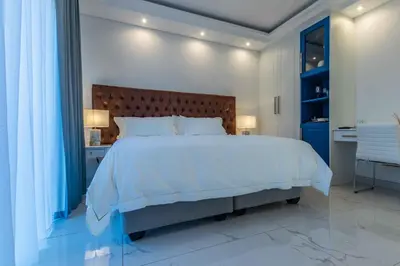 a bedroom with a large white bed and a blue cabinet at Oceanway Boutique Hotel/Conference in Cape Town