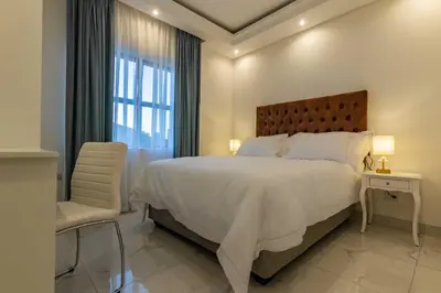a white bedroom with a large bed and a chair at Oceanway Boutique Hotel/Conference in Cape Town