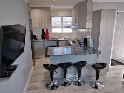 a kitchen with two bar stools and a counter at Birds Holiday Accommodation 2 in Cape Town