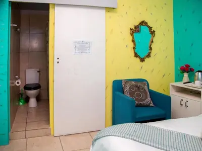 a room with a bed and a bathroom with a toilet at Relaxing Guest House in the Heart of Ndabeni in Cape Town