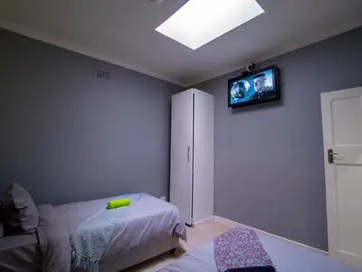 a bedroom with a bed and a tv on the wall at Relaxing Guest House in the Heart of Ndabeni in Cape Town