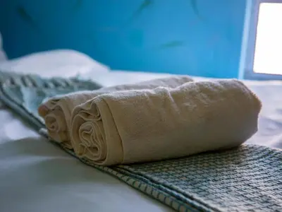 a rolled up towel sitting on top of a bed at Relaxing Guest House in the Heart of Ndabeni in Cape Town