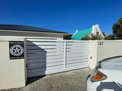 a white privacy fence with a car parked next to it at 147 Abalone-Inn in Hermanus